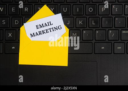 Vista dall'alto del testo di marketing e-mail su blocco note in una busta con sfondo laptop. E-mail marketing concetto Foto Stock