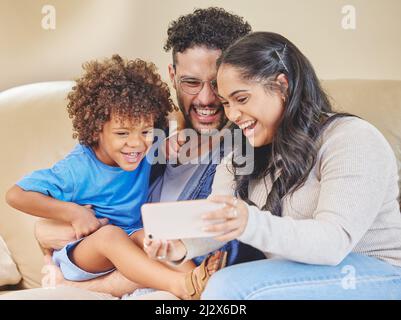 Sorridi per la macchina fotografica e dici il formaggio. Scatto di una giovane famiglia che prende insieme un selfie. Foto Stock