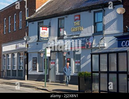 Uomo che cammina accanto al pub Griffin - chiuso e chiuso - su High Street, Market Weighton, East Yorkshire, Inghilterra Regno Unito Foto Stock