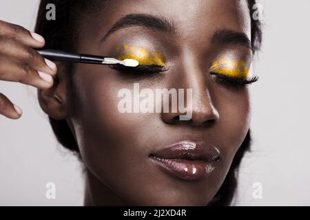 Provare qualcosa di diverso e di colore al di fuori delle linee. Studio girato di una bella giovane donna applicazione trucco occhi. Foto Stock
