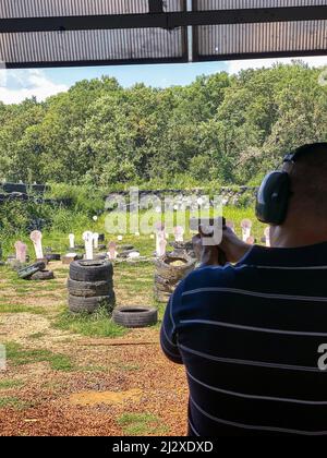 Pistola a fuoco uomo a bersaglio nel campo di tiro all'aperto Foto Stock