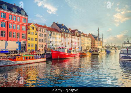 Un'antica barca da pesca rossa e bianca si erge tra le altre navi e yacht vicino alle vecchie case multicolore nel canale di Nyhavn. Copenaghen, Danimarca Foto Stock