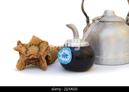 Una zucca di mate con una rosetta argentina, una pasticceria fritta e un bollitore, isolato su bianco Foto Stock