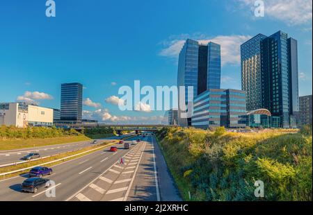 Edifici moderni dell'hotel Crowne Plaza Copenhagen Towersand e dell'autostrada Øresundsmotorvejen a Ørestad, Copenhagen, Danimarca Foto Stock