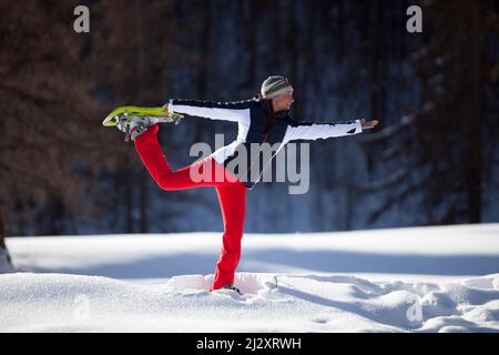 Serre-Chevalier (Alpi francesi, Francia sud-orientale): Gruppo di turisti durante un'escursione con racchette da neve. Donna che pratica una posa yoga Foto Stock