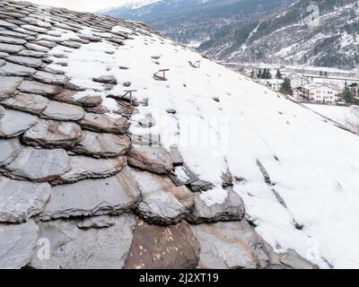 Vecchie tegole grigie, in parte ricoperte di neve, sfondo. Foto Stock