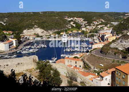 Bonifacio, Corsica meridionale: Case e negozi nella città bassa e il porto turistico con yacht e barche a vela lungo la banchina vista dalla cittadella (u Foto Stock