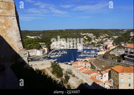 Bonifacio, Corsica meridionale: Case e negozi nella città bassa e il porto turistico con yacht e barche a vela lungo la banchina vista dalla cittadella (u Foto Stock