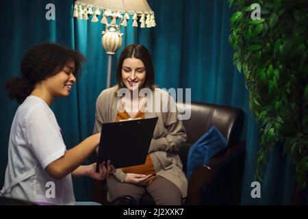 Felice giovane donna incinta caucasica parlare con ginecologo o psicologo in clinica privata o ospedale. Sorridente signora godere la gravidanza hanno c Foto Stock