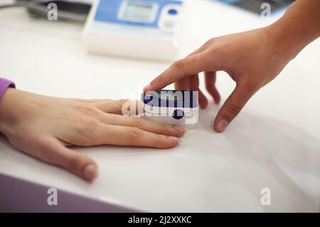 Donna in gravidanza con pulsossimetro sul dito. Medico che misura il livello di saturazione di ossigeno durante la visita in gravidanza con coronavirus a hom Foto Stock