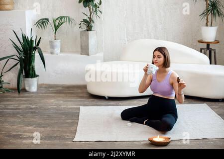La donna di Pregnat sta tenendo una bottiglia di olio essenziale e gocciolandolo in una lampada aromatica per aromaterapia e calma atmosfera rilassante, concentrazione su di me Foto Stock