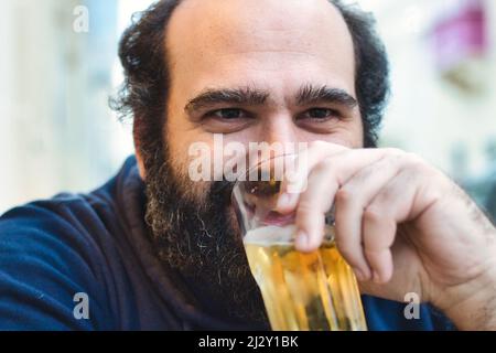 Uomo bearded che beve birra lager da un bicchiere Foto Stock