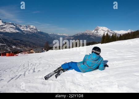Sciatore seduto sulla pista guardando un bellissimo paesaggio nella zona sciistica di Chamonix & Mont Blanc, Alpi francesi Foto Stock