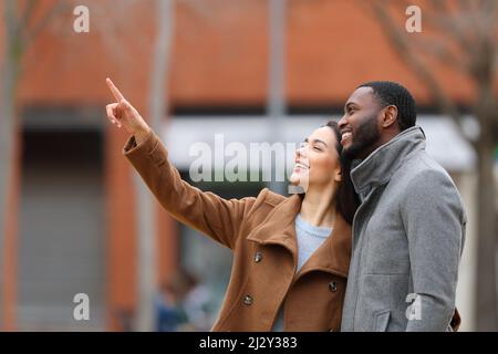 Coppia interrazziale che punta e guarda via in strada Foto Stock