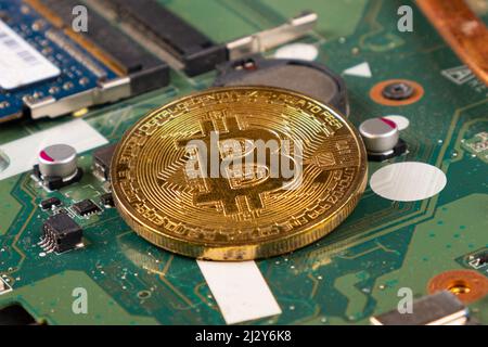 moneta d'oro bitcoin sul primo piano della scheda madre, criptovaluta btc. Foto Stock