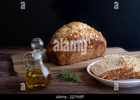 Primo piano di una pagnotta di pane fatto in casa e fette pronte per essere immerse nell'olio d'oliva. Foto Stock