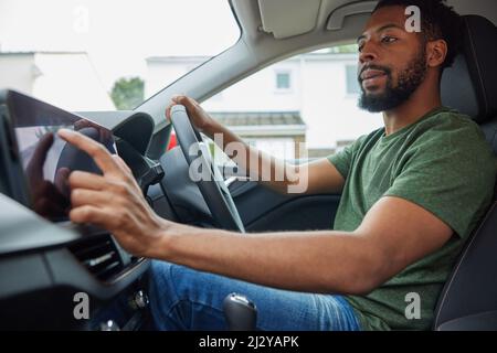Uomo che utilizza il touch screen durante la guida della vettura Foto Stock