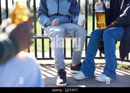 Primo piano di adolescenti minorenni che bevono alcol nel Parco Foto Stock