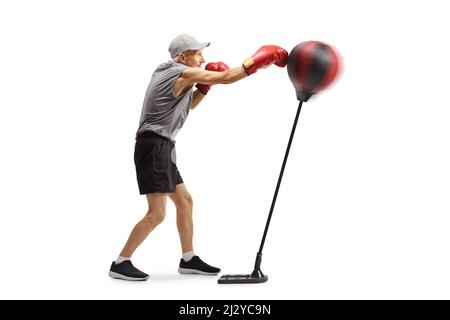 Elderely uomo che puncia un sacco da boxe indipendente isolato su sfondo bianco Foto Stock