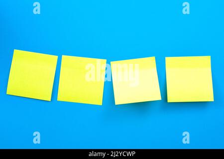 Cultura aziendale, lavoro di squadra e tema di comunicazione sul luogo di lavoro con 4 (quattro) note adesive gialle o promemoria adesivi isolati su blu ba