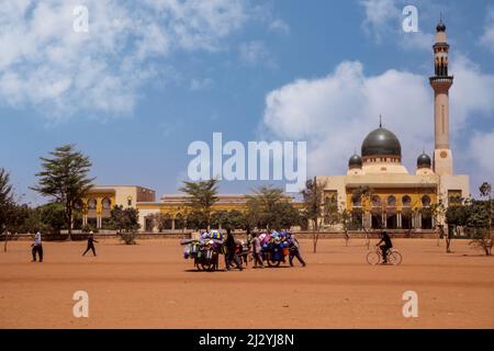 Niamey, Niger. La Grande Moschea di Niamey. I fornitori di Secchielli in plastica e teiere in primo piano, spingendo i loro carri. Foto Stock