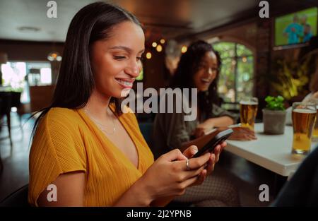 femmina afroamericana fuori per bevande sms sul telefono cellulare Foto Stock