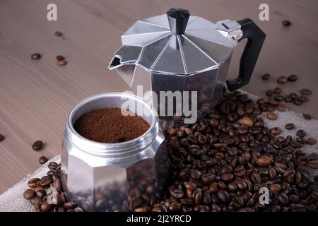 Macchina per caffè geyser disassemblata su superficie in legno. Chicchi di caffè. Foto Stock