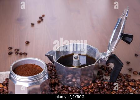 Macchina per caffè geyser disassemblata su superficie in legno. Chicchi di caffè. Foto Stock