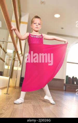 l'affascinante bambina sogna di diventare ballerina. La ragazza nel tutu rosa sta ballando, tenendo in mano al bar.Baby ragazza sta studiando balletto. Foto Stock