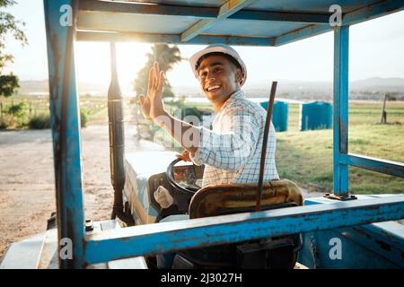 Fuori per controllare sul resto dei miei raccolti. Shot di un giovane agricoltore che guida un trattore in un'azienda agricola. Foto Stock