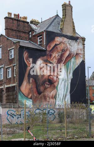 Murale sul lato di un edificio un uomo volto, cracking e nel dolore Foto Stock