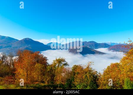 Catena montuosa al confine con l'Italia sul Lago di Lugano con cielo nuvoloso e luce del sole a Caslano, Ticino in Svizzera. Foto Stock