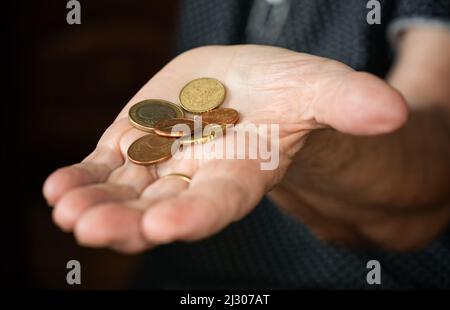 Coppia di monete in euro in mano anziana donna anziana Foto Stock