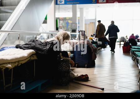 Dnipro, Ucraina - 04 aprile 2022: Una donna anziana disabile siede su un letto in un centro commerciale convertito per i rifugiati a Dnipro. Foto Stock