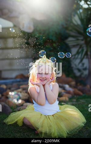 Ceneri in un mondo proprio. Full length shot di una bambina adorabile che gioca fare credere all'aperto. Foto Stock