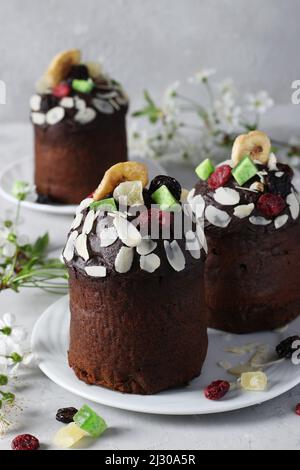 Dolci di Pasqua al cioccolato con frutta candita su sfondo grigio. Pasqua primavera ancora vita. Formato verticale Foto Stock