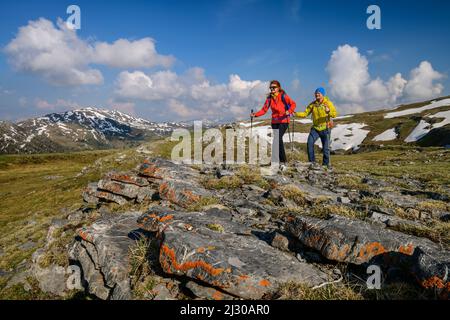 Escursioni uomo e donna su Königstuhl, rocce ricoperte di lichen in primo piano, Königstuhl, Nockberge, Nockberge-Trail, Unesco Nockberge Biosphere Park, Gurktal Alpi, Carinzia, Austria Foto Stock