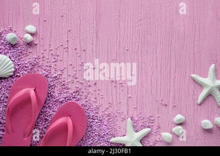 Estate al mare. Infradito in gomma rosa, pantofole su ciottoli con stelle marine e ciottoli, studio concept. Sfondo rosa con texture, spazio di copia. Foto Stock