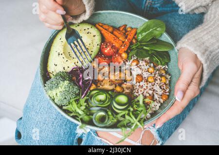 Donna che mangia pasto sano. Ciotola con riso, quinoa, avocado, cetrioli, broccoli e cetrioli. Dieta sana, pranzo o cena. Cibo sano piatto Foto Stock