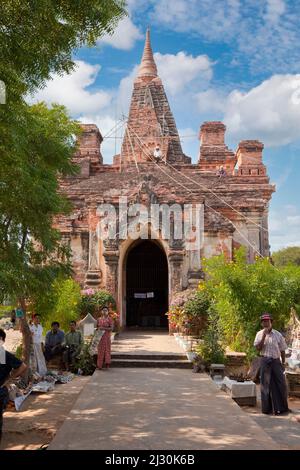 Myanmar, Birmania. Manuha Tempio, Bagan, 11th. Secolo. Lavori di riparazione in corso. Venditori di souvenir di fronte. Foto Stock