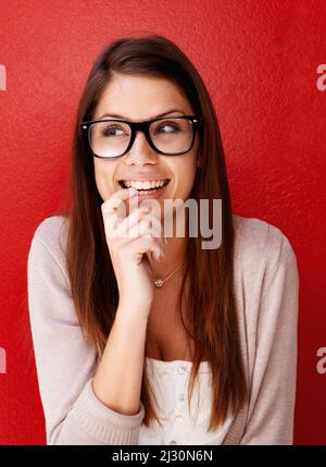 Non vedo l'ora. Vista ritagliata di una giovane donna che indossa occhiali e guarda via con un sorriso. Foto Stock