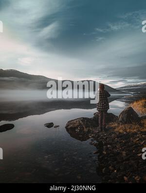Il turista ammirando il cielo riflessi sul lago in Svezia Foto Stock