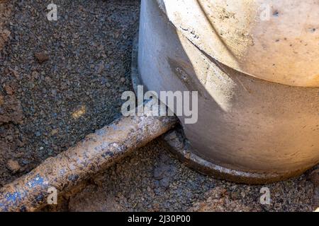 installazione di una conduttura sotterranea, inserimento di un tubo di plastica nera in un pozzo fatto di anelli di calcestruzzo sul fondo della trincea, selettivo f Foto Stock