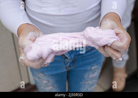 Il bambino rugge la calce nelle mani. Sostanza appiccicosa. Prodotti a base di farina con proprietà di trazione. Due mani si strinzano una cosa leggera e morbida. Foto Stock