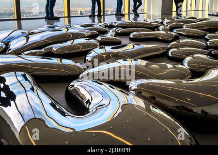 I piedi e le gambe del tourstista nella sala Cloud al Summit One Vanderbilt con sculture sul pavimento disegnate da Yayoi Kusam Foto Stock