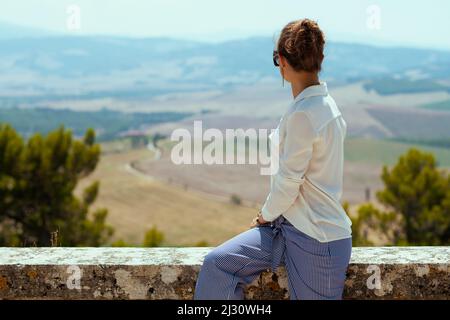 Viaggi in Italia. Visto da dietro elegante viaggiatore solista donna a Pienza in Toscana, Italia. Foto Stock