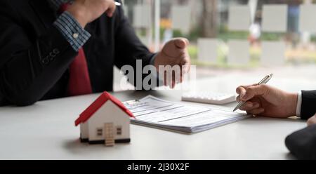 Agente immobiliare ha proposto termini e condizioni ai clienti che firmano contratto di acquisto casa con assicurazione, accordo per firmare l'acquisto Foto Stock