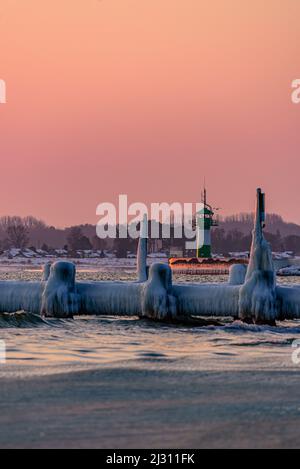 Vecchio molo di legno ghiacciato sulla spiaggia, sullo sfondo molo luce (faro), Travemünde, Baia di Lübeck, Schleswig Holstein, Germania Foto Stock