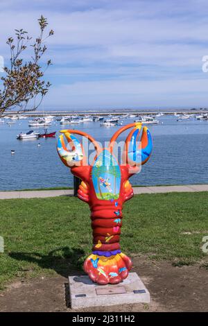 PLYMOUTH, USA - SEP 26, 2017: Scultura colorata di aragosta dipinta da artisti locali sul lungomare di Plymouth con il porto e le navi sullo sfondo. Foto Stock