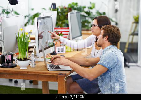 Mettendo insieme le loro menti. Scatto di un giovane designer al lavoro in un ufficio. Foto Stock